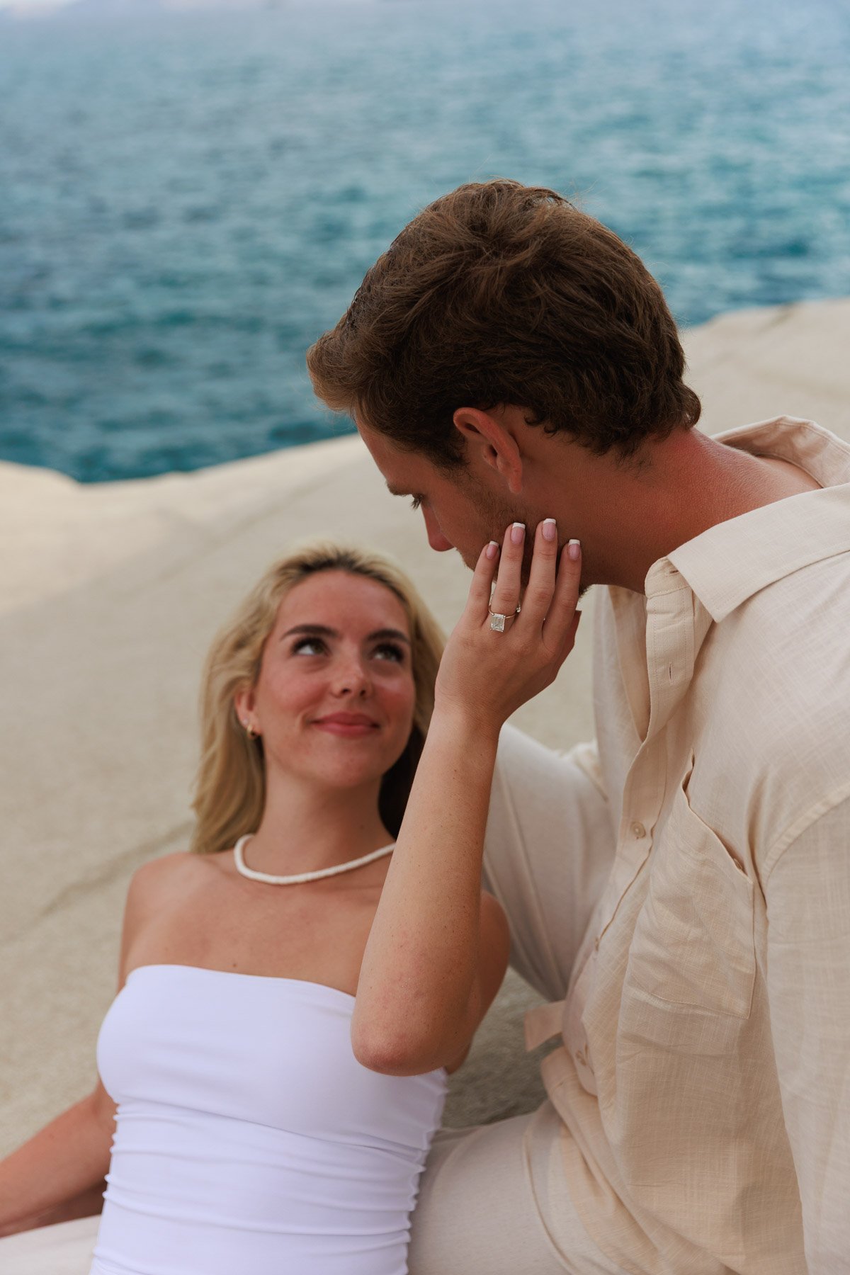 Engaged couple in Milos, Greece by the sea, with the woman showing her engagement ring
