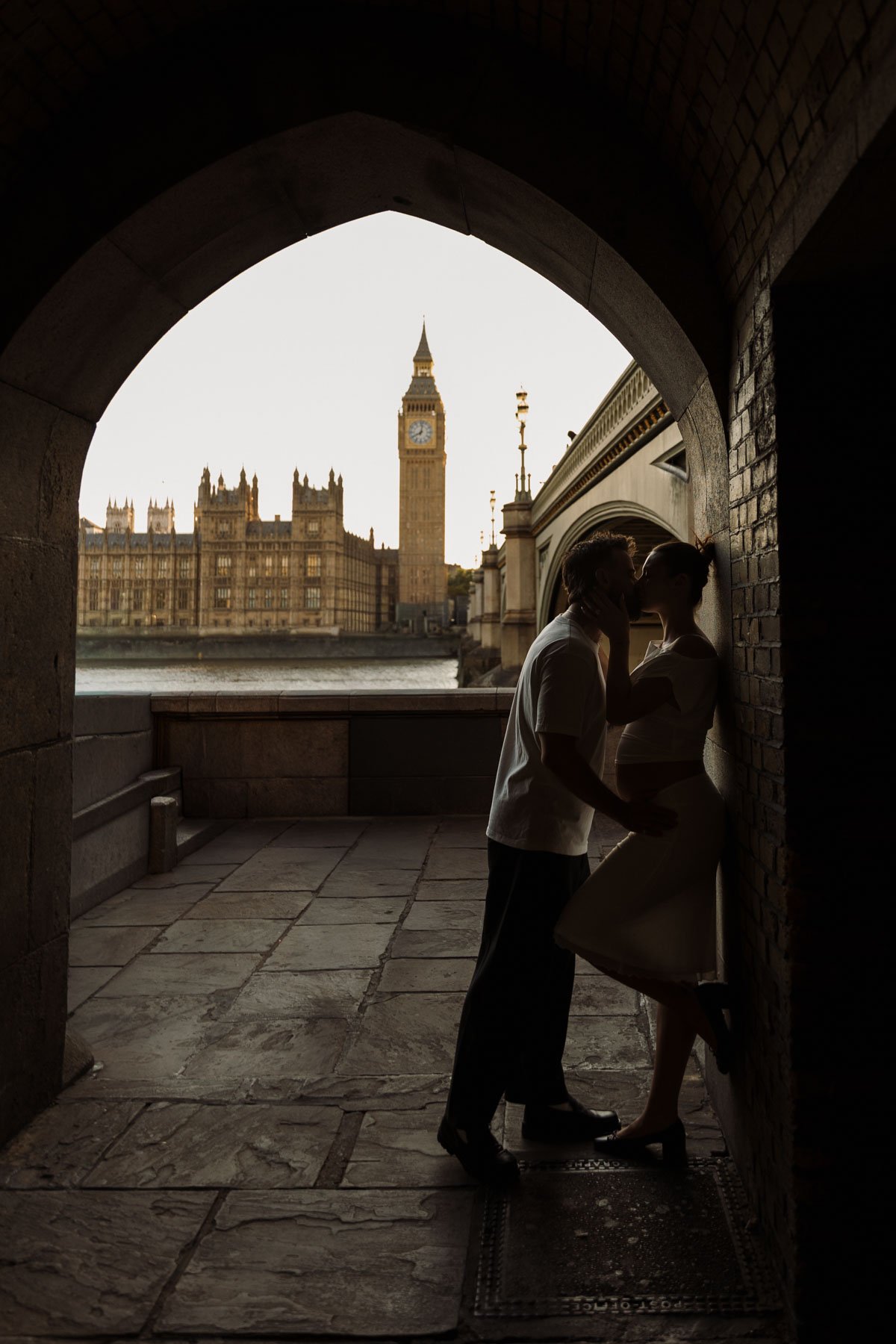Couple kissing beneath an archway in London with Big Ben and the Houses of Parliament in the background
