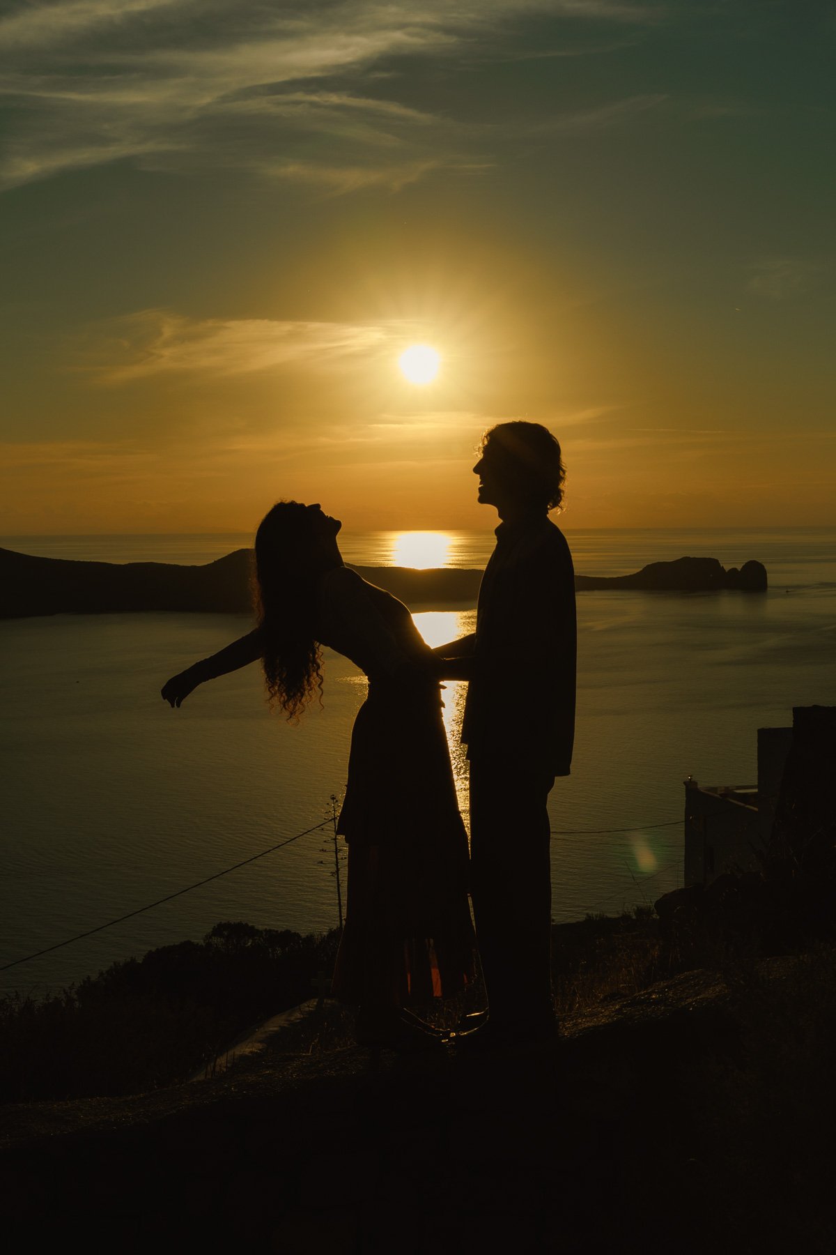 Silhouette of an engaged couple overlooking the sea at sunset in Milos, Greece
