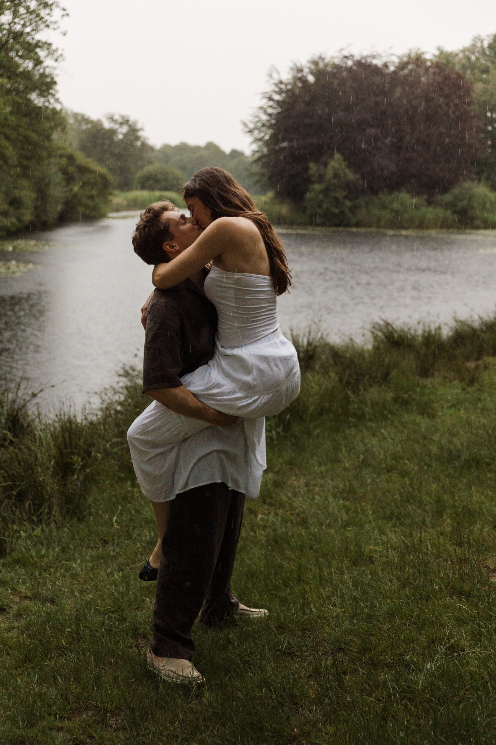 Couple kissing in the rain beside a lake during a romantic couples photography session in the Netherlands