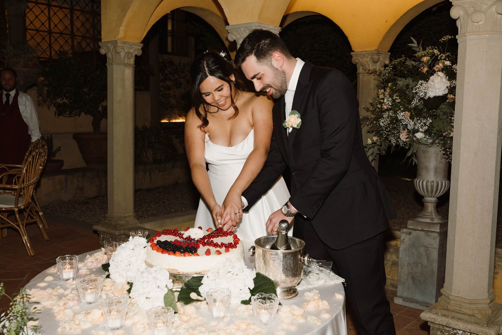 Bride and groom cutting their wedding cake during an evening reception in Tuscany, Italy